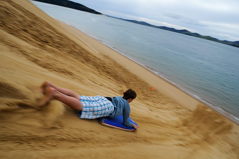 sliding down a sand dune on a boogie board